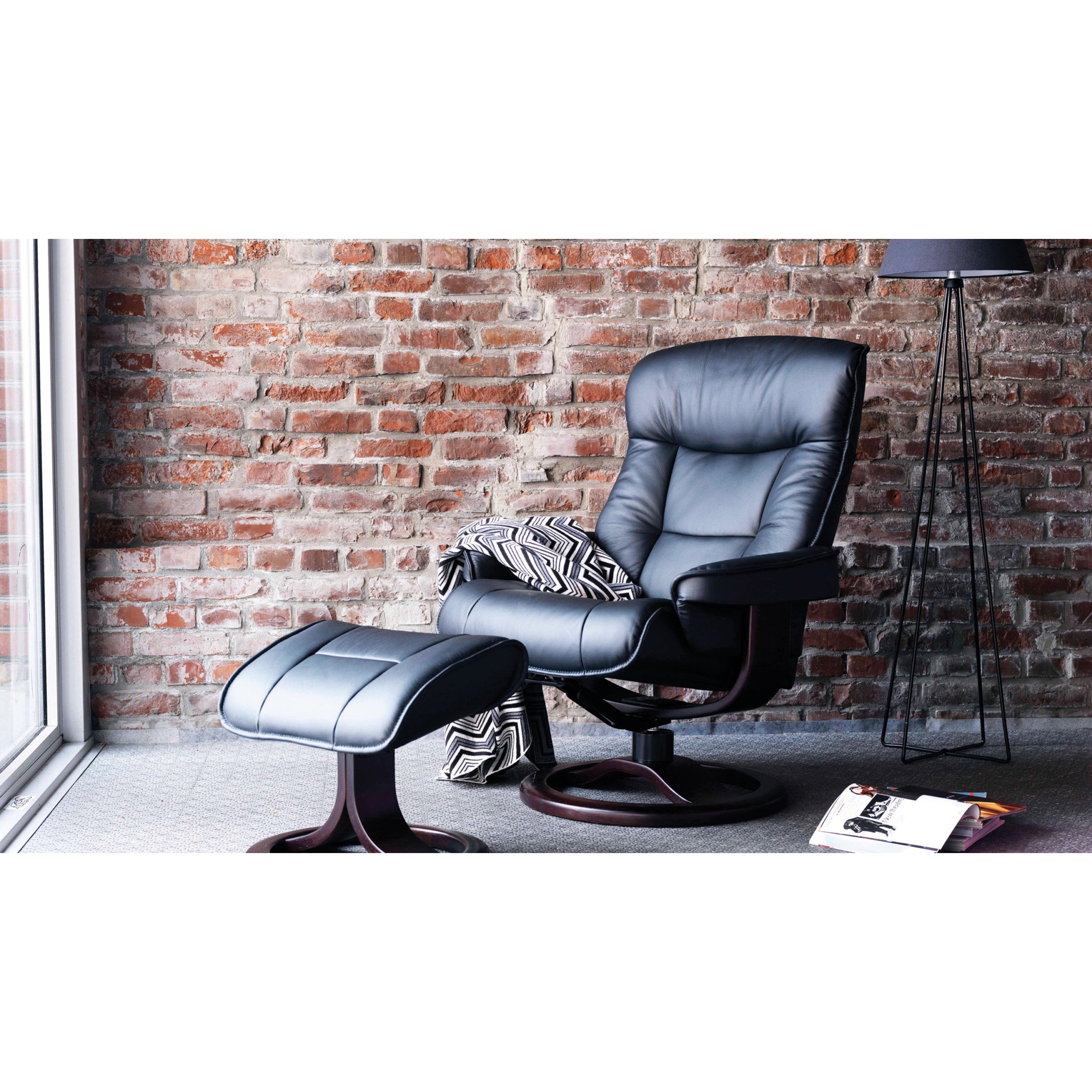 Gray recliner chair with ottoman against a brick wall