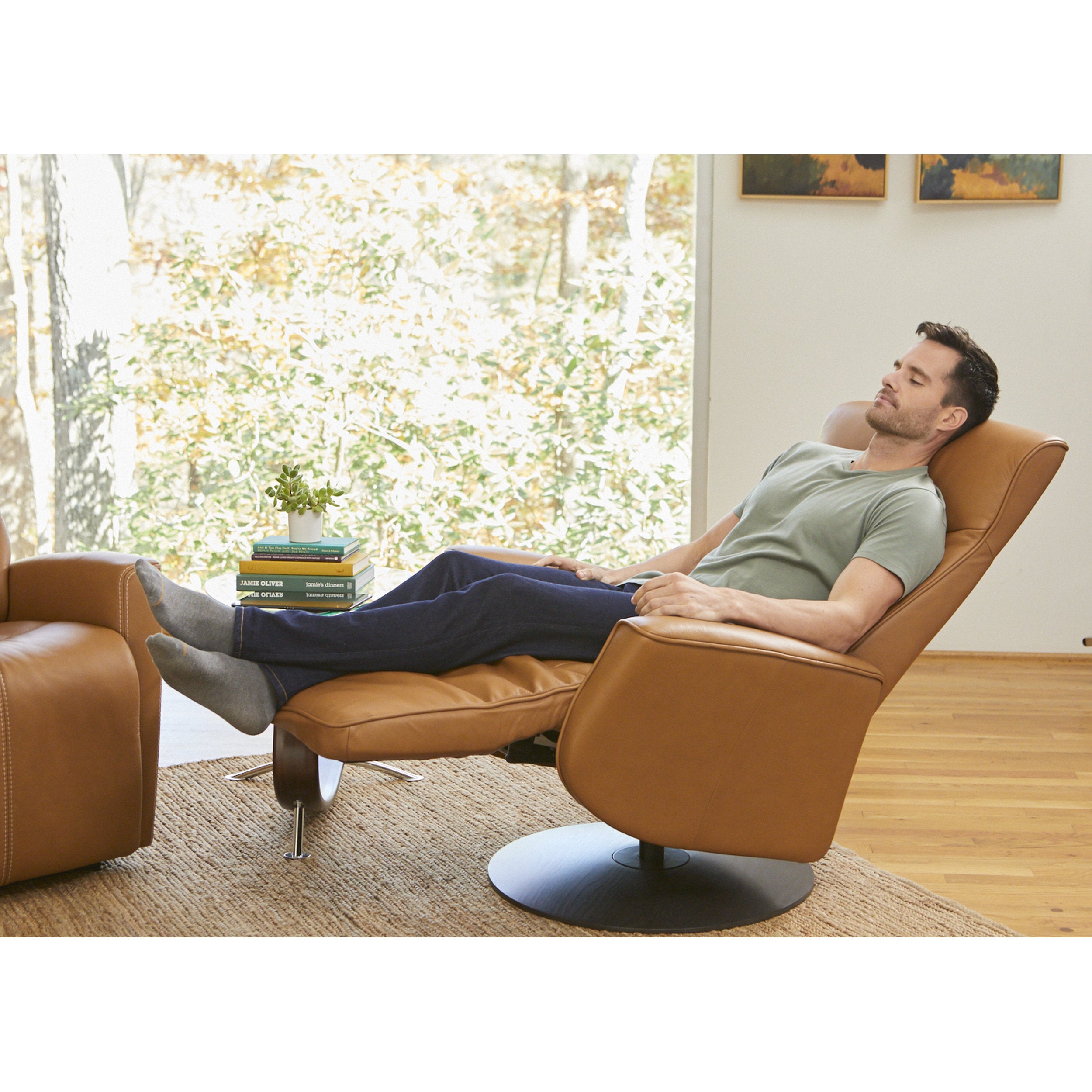 Man relaxing in a brown leather chair in a bright living room.