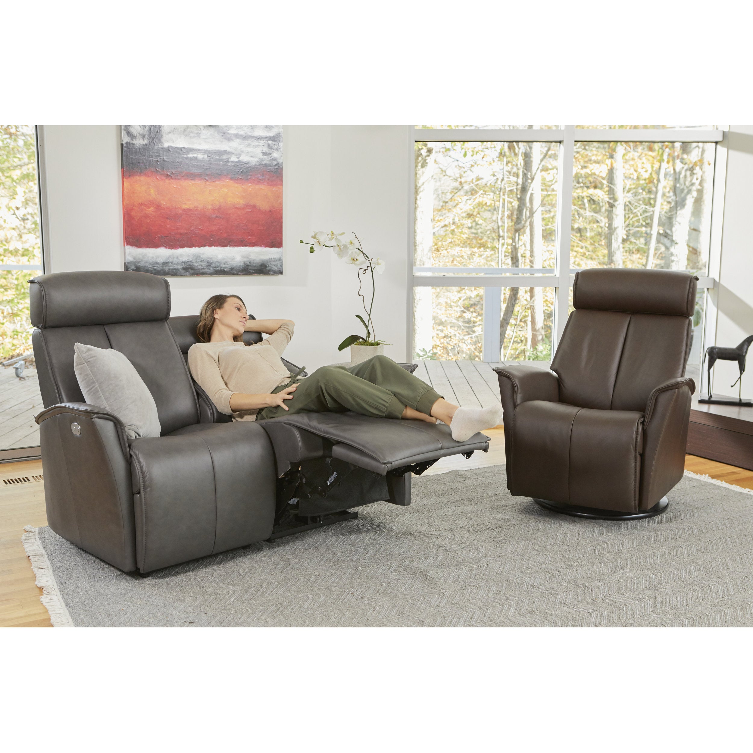 Woman relaxing on a large gray recliner in a living room with a second recliner chair.