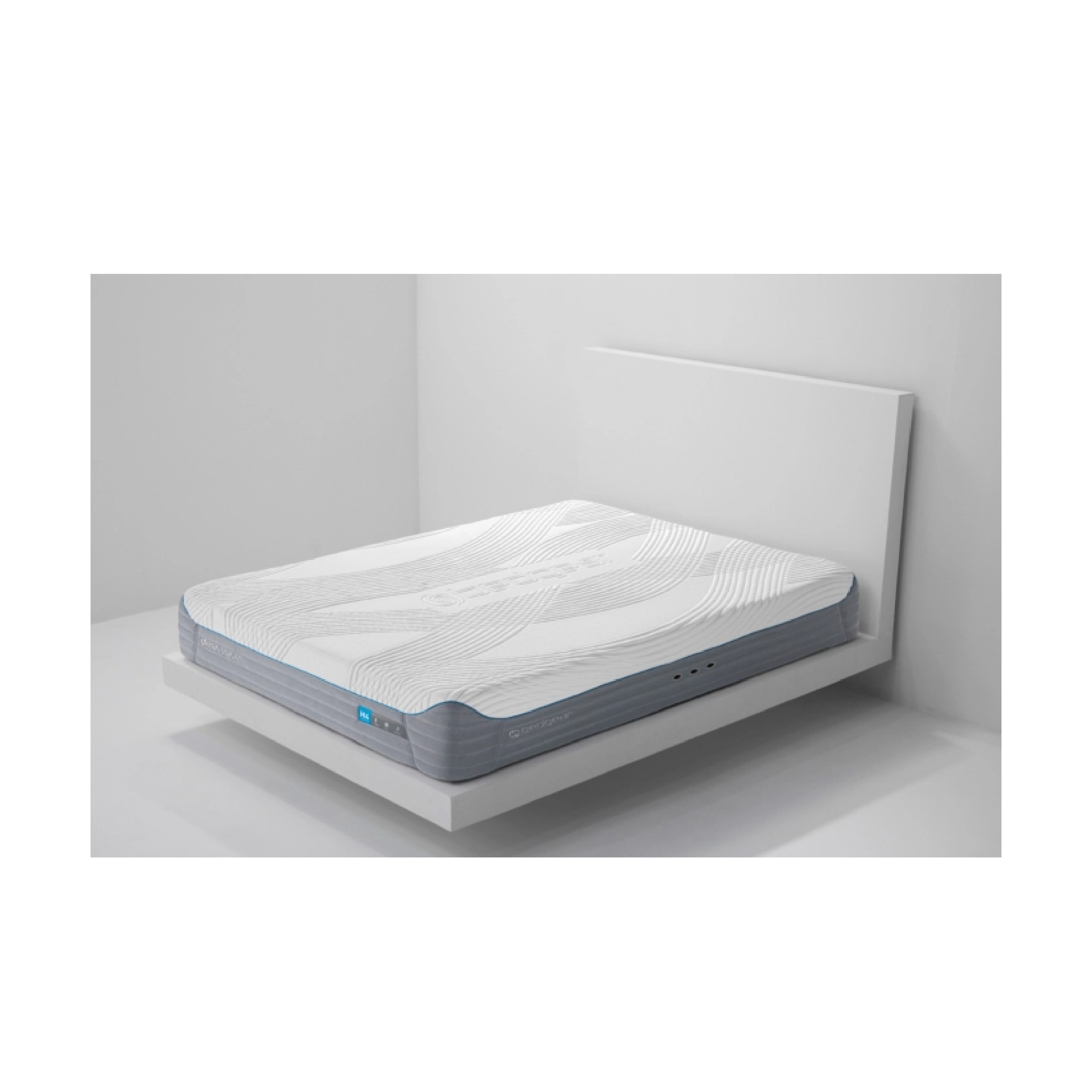 A mattress with a patterned gray and white surface, situated on a bed frame in a room with minimalistic white walls and a white bedside table.