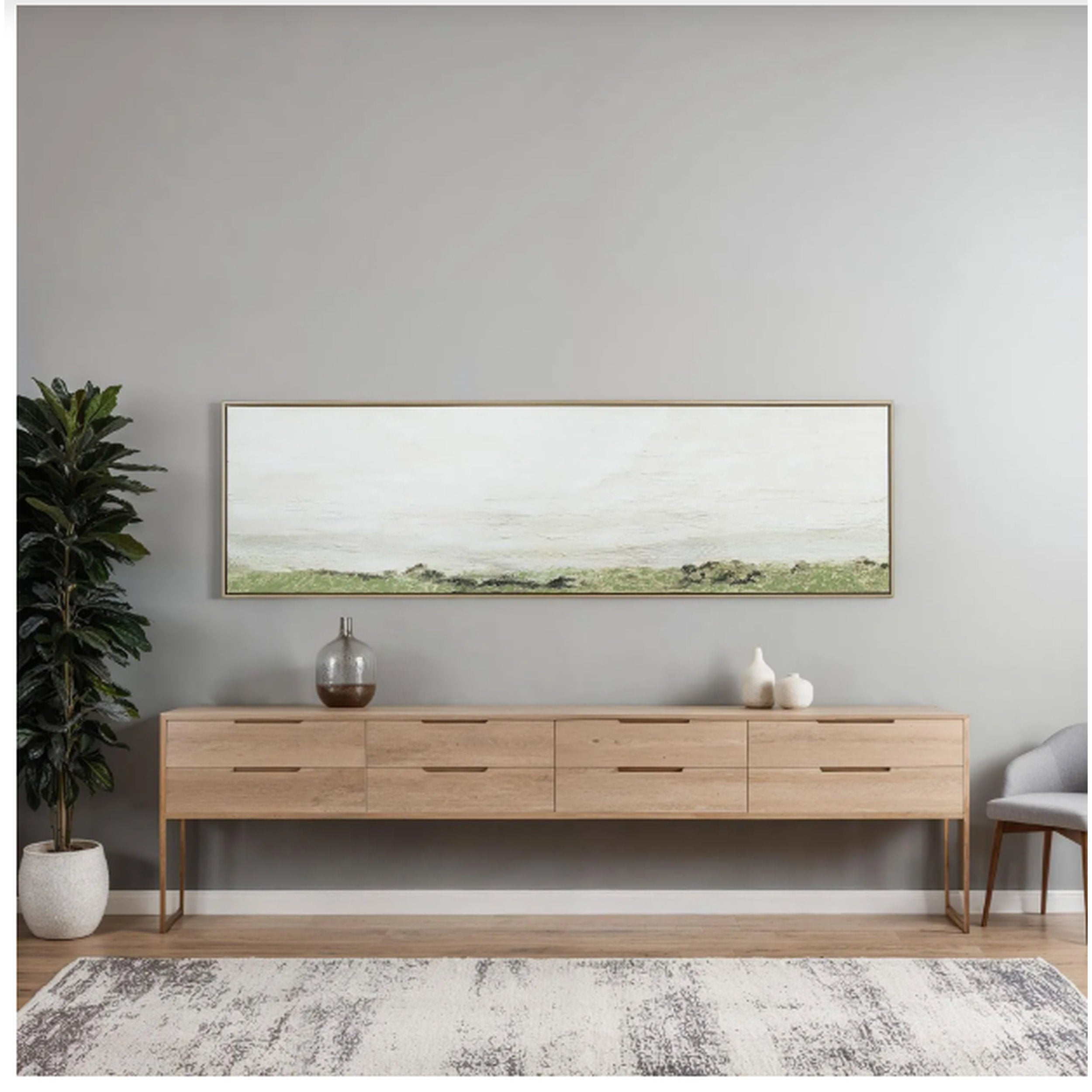 Wooden sideboard against a gray wall with a large framed picture above it.
