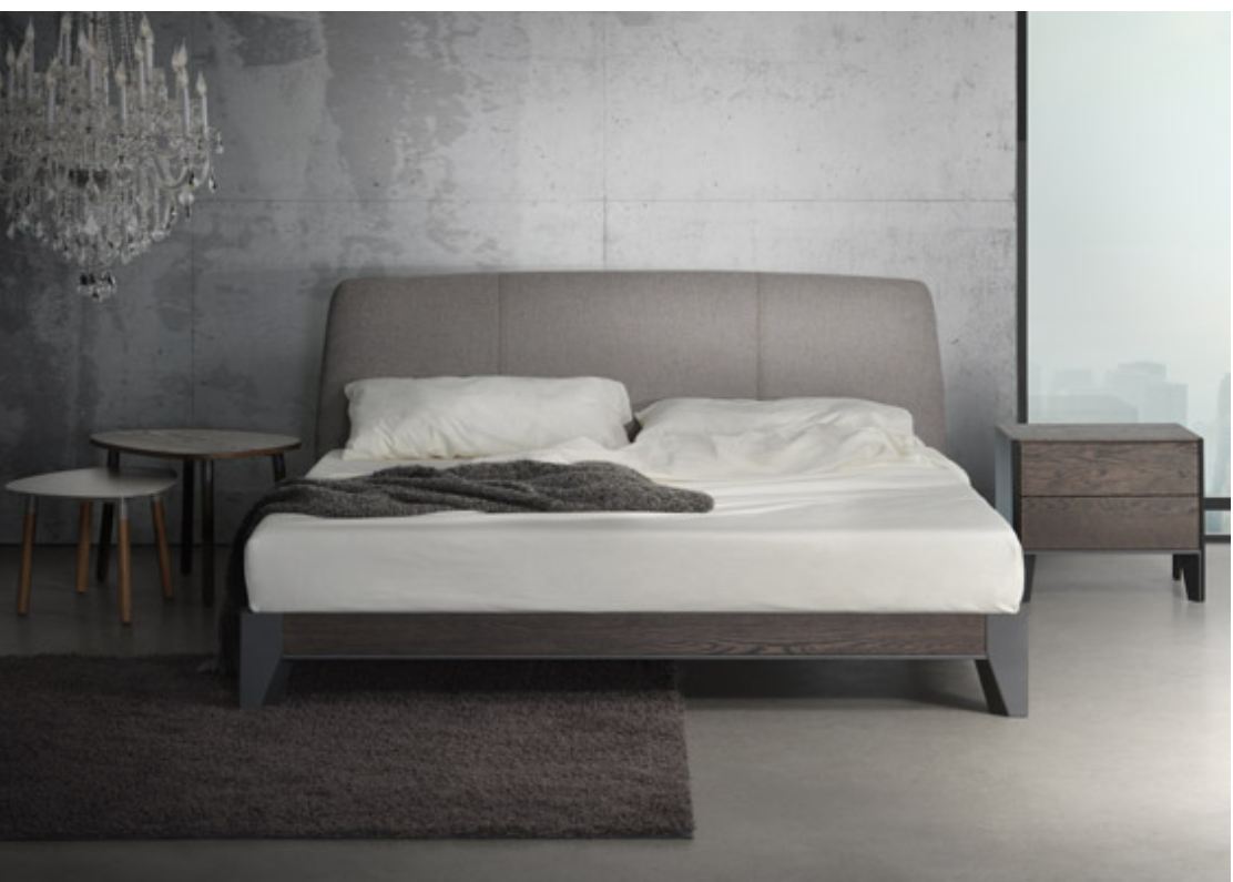 A modern platform bed frame with a white mattress, oak wood legs, and a grey upholstered headboard.