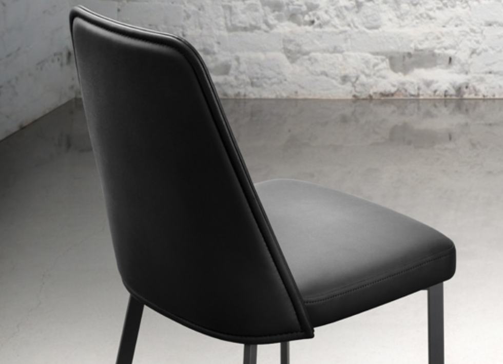 A black upholstered dining chair with a fully welded frame and high resilience foam comfort seat, against a white background.