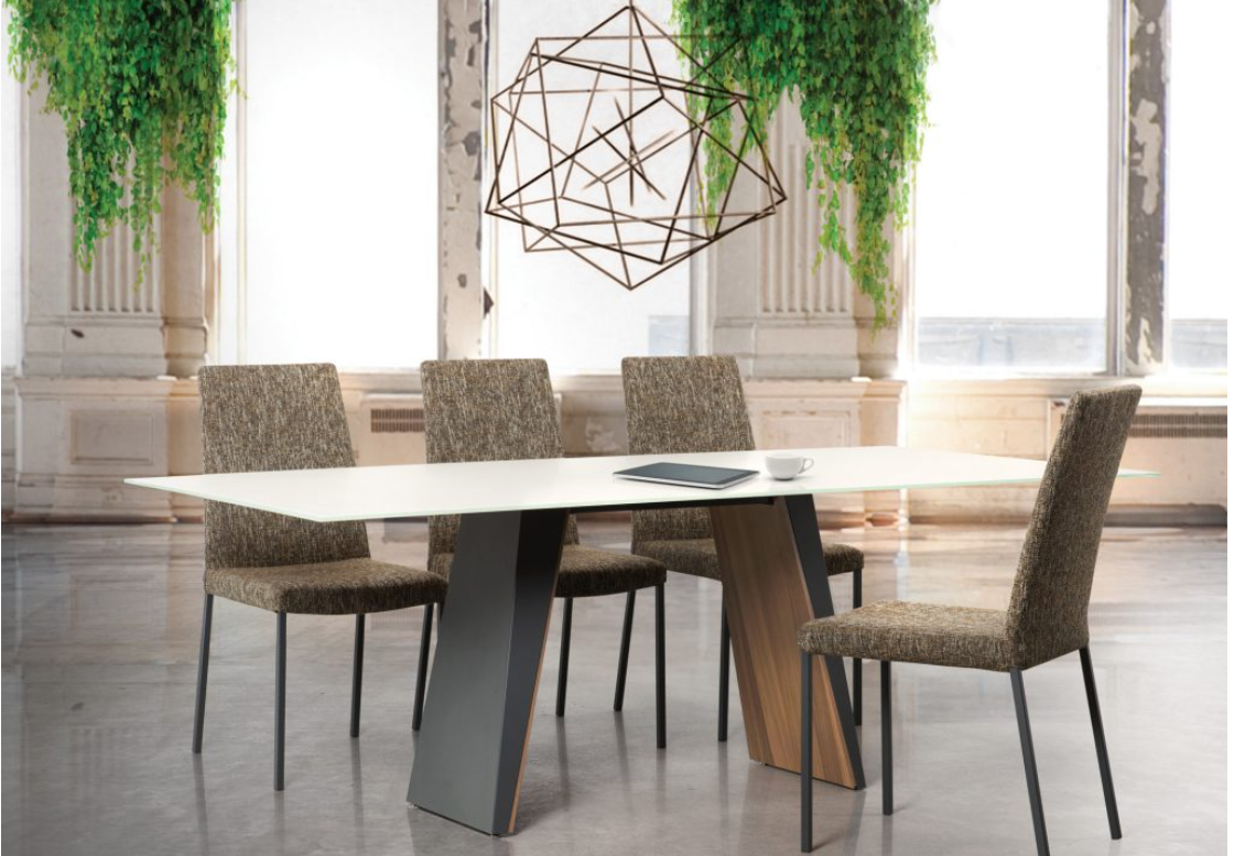 A rectangular dining table with a metal and wood veneer base and a flat glass top