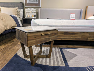 Wooden side table with marble top in a bedroom setting