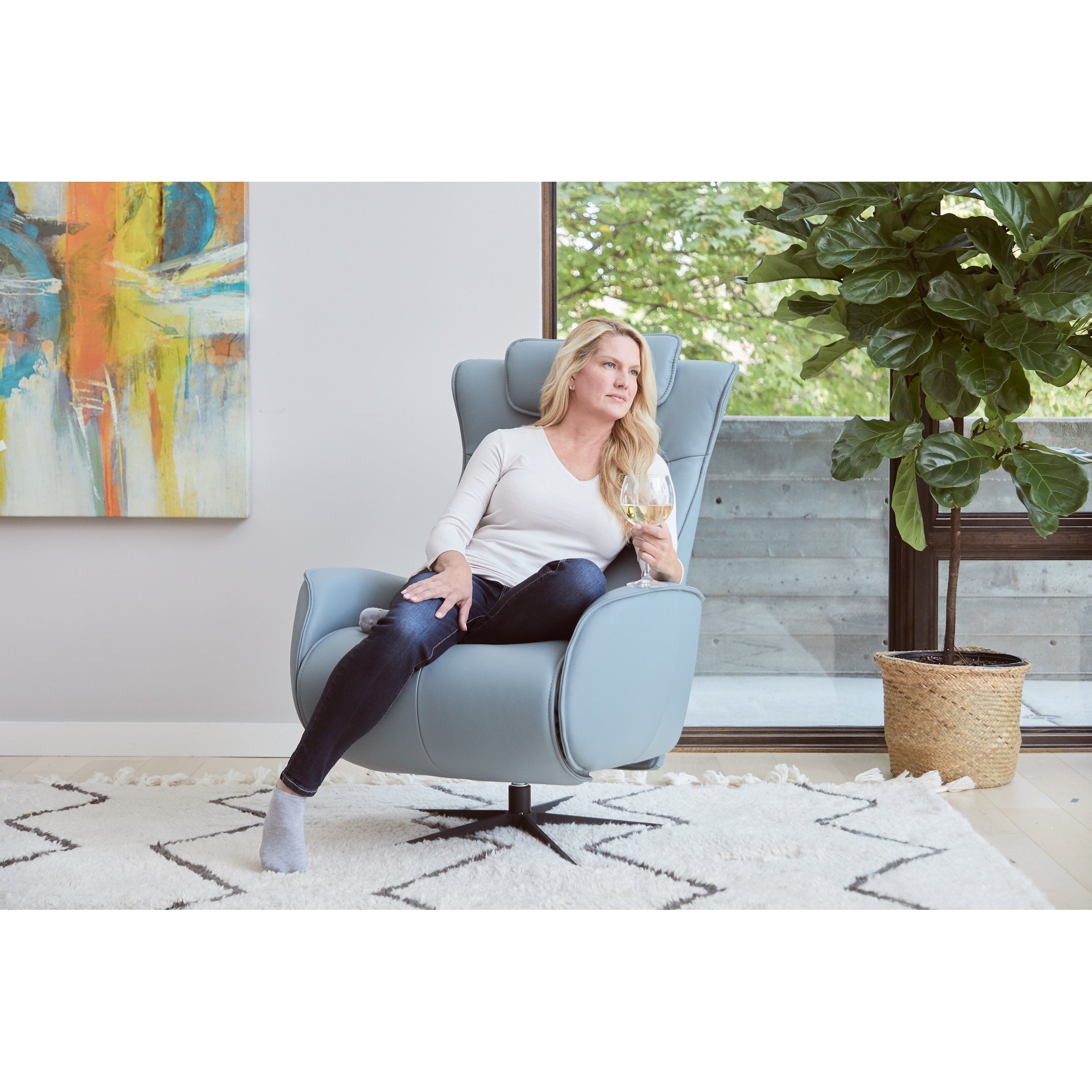 Woman sitting in a modern chair holding a glass of wine in a stylish living room.