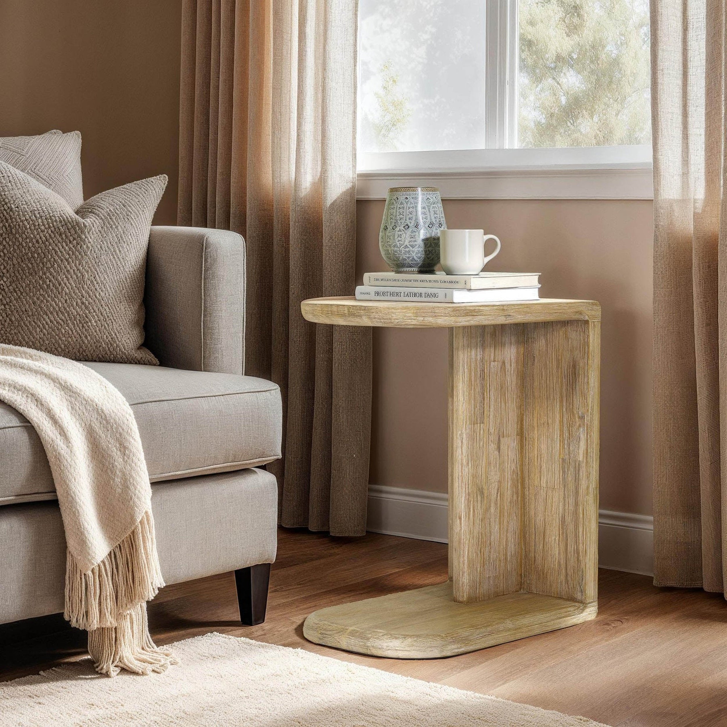 Haru C Shaped Side Table by LH Home in light oak finish, solid wood with curved pedestal base, displaying books and mug.