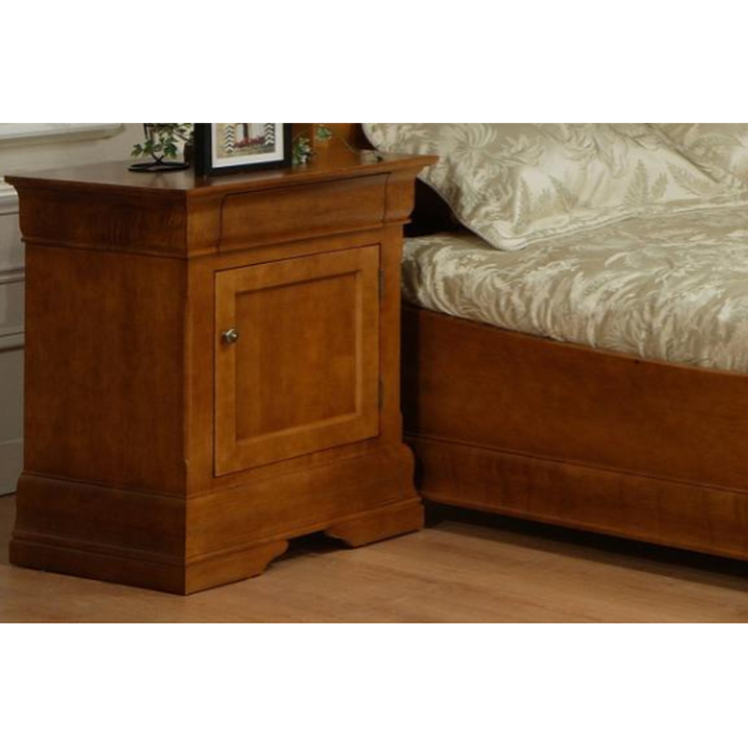 Wooden nightstand next to a bed with patterned bedding