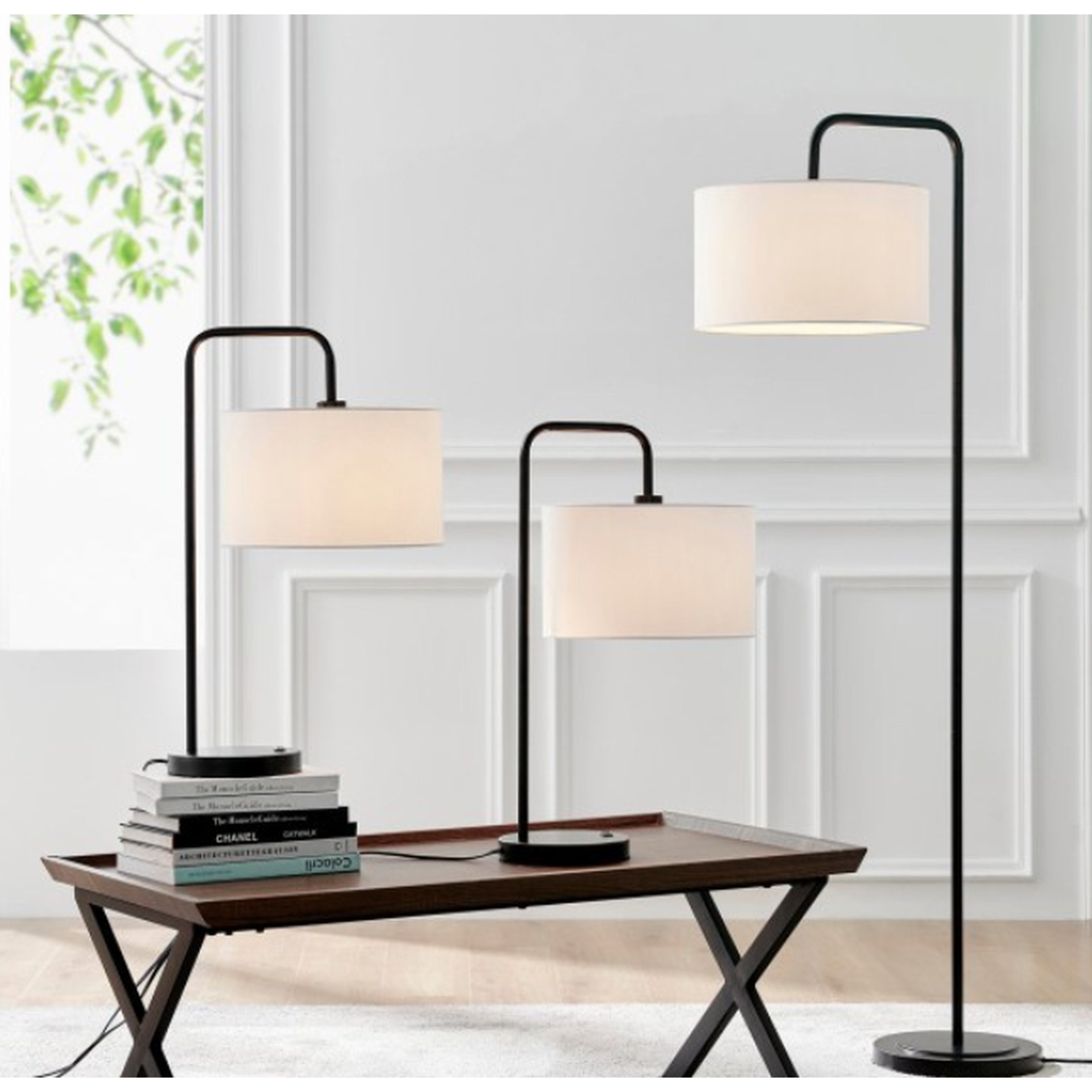 Three floor lamps with white lampshades on a wooden table against a light-colored wall.